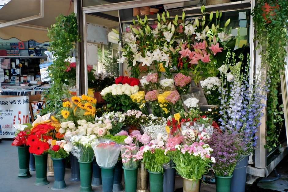 A vibrant display of fresh floral arrangements outside a florist shop on Brompton Road, Knightsbridge, featuring a variety of flowers including white lilies, pink lilies, red gerberas, white roses, pi