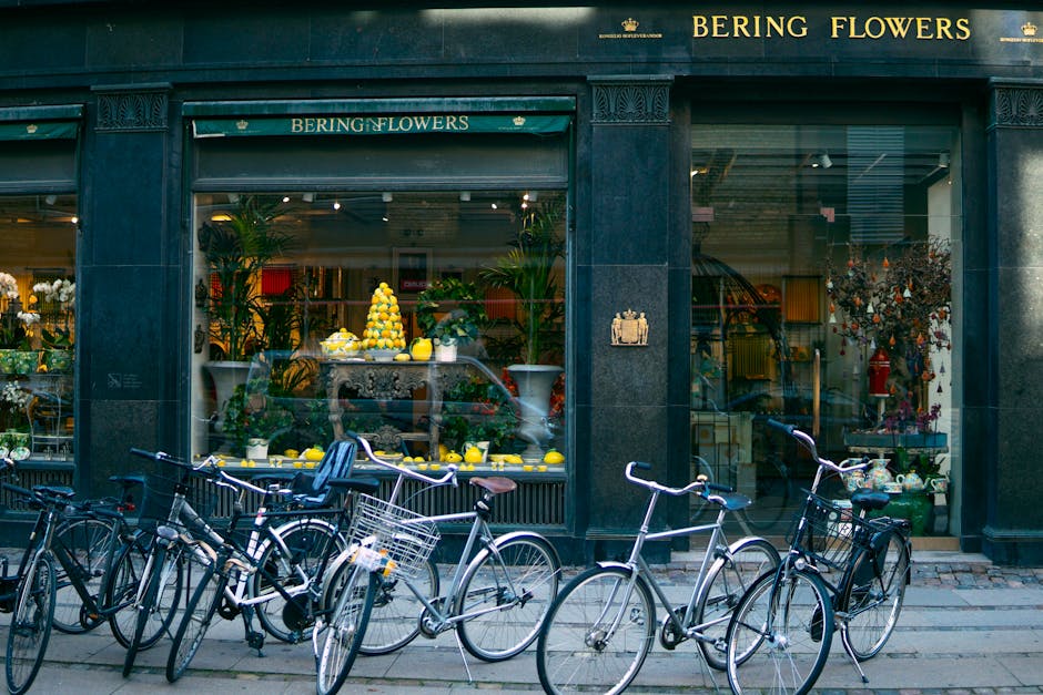 The storefront of Bering Flowers on Brompton Road in Knightsbridge features large glass windows showcasing an elegant floral display. Inside, a tiered arrangement of vibrant yellow lemons and lemon-th